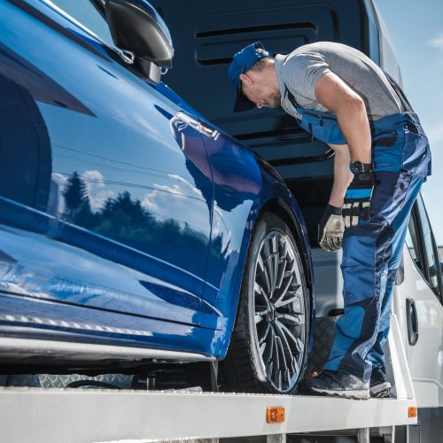 Car Repossession Worker Securing Vehicle on His Towing Truck. Vehicle Financing and Repo Company.